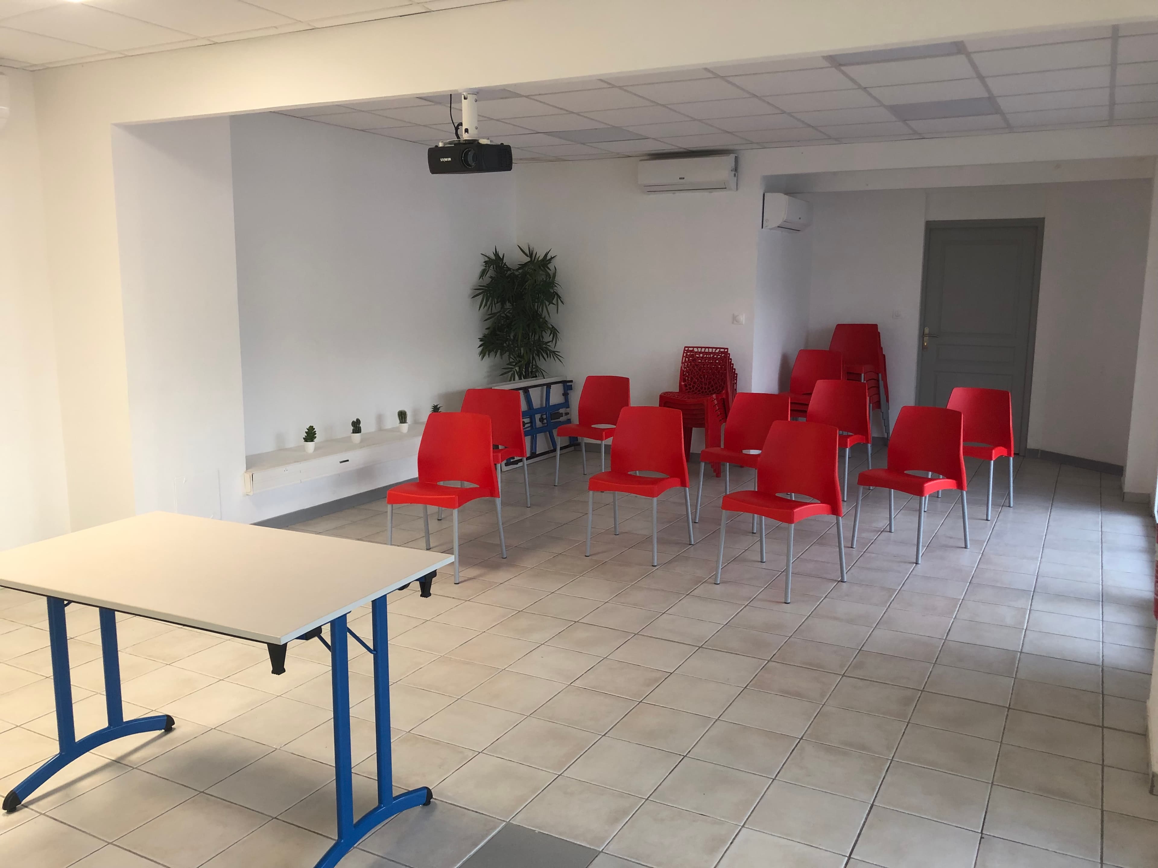 La salle disposée en réunion, chaises rouges face à une table